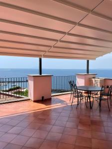 a table and chairs on a deck with a view of the ocean at Coral Blue Apartment in Piano di Sorrento +15 photos