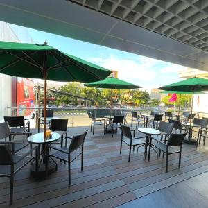 雅加達的住宿－Grand G7 Hotel Pasar baru，一个带桌椅和绿色遮阳伞的庭院