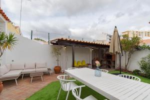 a patio with a white table and chairs and an umbrella at Setúbal Oasis House in Setúbal