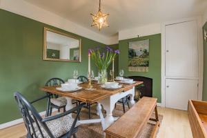 a dining room with green walls and a wooden table with chairs at Cliffeside Cottage in Kingsdown