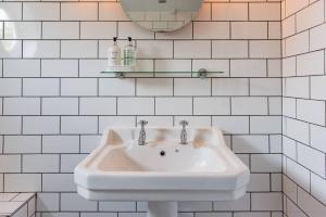 a white sink in a white tiled bathroom at Cliffeside Cottage in Kingsdown +34 photos