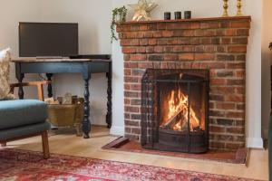 a brick fireplace with a fire in it at Cliffeside Cottage in Kingsdown