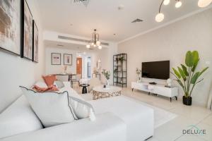 a living room with a white couch and a tv at Harmonious 1BR at Al Shera Tower JLT by Deluxe Holiday Homes in Dubai