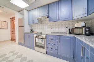 a blue kitchen with stainless steel appliances and blue cabinets at Harmonious 1BR at Al Shera Tower JLT by Deluxe Holiday Homes in Dubai