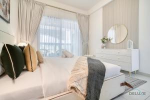 a white bedroom with a bed and a mirror at Harmonious 1BR at Al Shera Tower JLT by Deluxe Holiday Homes in Dubai