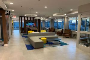 a lobby with a couch and chairs and a tv at Microtel Inn & Suites by Wyndham Rehoboth Beach in Rehoboth Beach