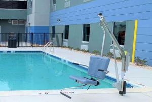 a swimming pool with a chair in front of a building at Microtel Inn & Suites by Wyndham Rehoboth Beach in Rehoboth Beach