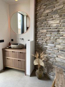 baño con pared de piedra y espejo en Glundr! en Behelp