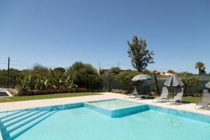 a swimming pool with two chairs and an umbrella at O PINHAL DO AVÔ in Almancil