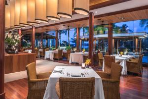 un restaurante con mesas y sillas blancas y ventanas en Andara Resort Villas en Kamala Beach