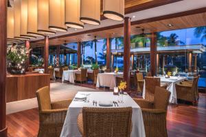 a restaurant with white tables and chairs and windows at Andara Resort Villas in Kamala Beach