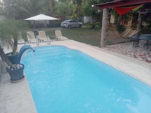 una gran piscina azul con sillas en un patio en Sunrise Hostel Farallon en Río Hato