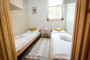 two beds in a small room with a window at ACTIVFARM DOMKI NA KASZUBACH Domek Dorotka in Gliśno