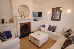 a living room with white furniture and a fireplace at Captains Cottage in Deal