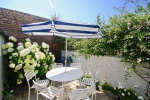 a table and chairs under a blue and white umbrella at Captains Cottage in Deal