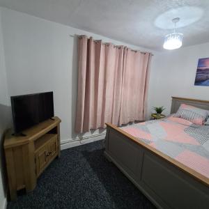 a bedroom with a bed and a flat screen tv at Freshen-Up Stays in Oakengates