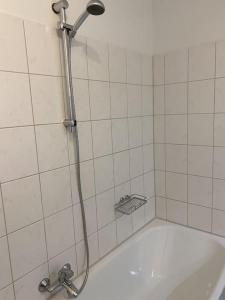 La salle de bains carrelée de blanc est pourvue d'une douche et d'une baignoire. dans l'établissement 4 Zimmer Wohnung mit 6 Betten nahe Hamburg, à Glinde