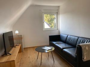 ein Wohnzimmer mit einem schwarzen Sofa und einem Fenster in der Unterkunft Appartement NikTen in Friedrichshafen