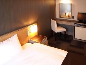 a bedroom with a bed and a desk and a television at HOTEL LiVEMAX Osaka Namba in Osaka