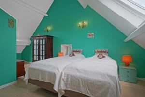 a bedroom with green walls and a bed with white sheets at Gîte du Jardin in Theux