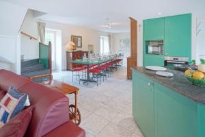 a kitchen and living room with green cabinets and a red couch at Gîte du Jardin in Theux
