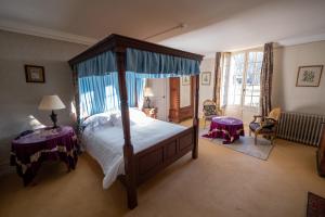 a bedroom with a canopy bed and two tables at Chateau Le Mas de Montet in Petit-Bersac