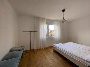 ein weißes Schlafzimmer mit einem Bett und einem Fenster in der Unterkunft Appartement NikTen in Friedrichshafen
