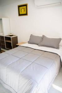 uma cama branca num quarto branco com uma mesa em Bello Monoambiente ZV212, Edif Zetta Village Airport em Colonia Mariano Roque Alonso