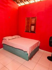 ein Schlafzimmer mit einer roten Wand, einem Bett und einem Fenster in der Unterkunft Casa 2 Gold Star Village in Majorlândia