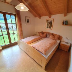 een slaapkamer met een houten bed en een groot raam bij Haus Lubach in Kals am Großglockner