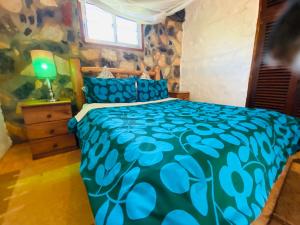 Schlafzimmer mit einem Bett mit blauer Decke in der Unterkunft HomeOnTheNile in Jinja