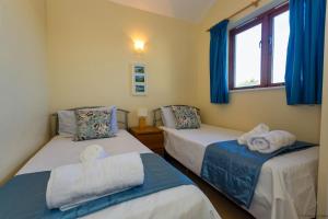 two beds in a room with blue curtains and a window at CROYDE DUNE LODGE 3 Bedrooms in Croyde