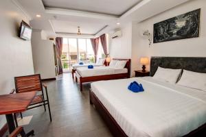 a hotel room with two beds and a table and chairs at Mad Monkey Hostel Siem Reap in Siem Reap