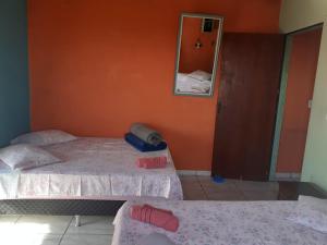 2 camas en una habitación con pared de color naranja en Casa Pôr do Sol, en São Thomé das Letras