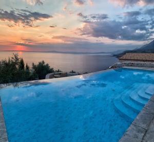 a large blue swimming pool with a view of the water at BASSA MAINA Villas & Suites in Areopoli