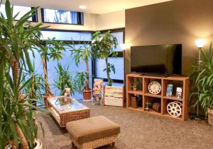 a living room with potted plants and a flat screen tv at HOTEL LiVEMAX BUDGET Gunma Numata in Numata