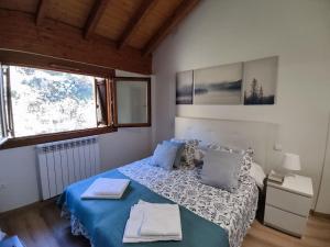 1 dormitorio con cama con sábanas azules y ventana en Casa Balcón de Los Pirineos - Gavín Biescas, en Gavín