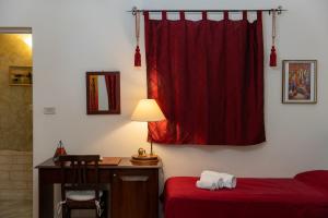ein Schlafzimmer mit einem Schreibtisch und einem roten Vorhang in der Unterkunft Aci B&B in Acireale