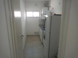 una pequeña cocina blanca con nevera y ventana en El Serrano, en Tandil 2 fotos más