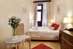 1 dormitorio con 1 cama y un jarrón de flores sobre una mesa en Gołębia 8 Residence, en Cracovia
