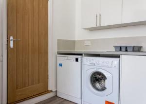 eine Küche mit einer Waschmaschine und einer Holztür in der Unterkunft Modern 5 Bed Near LFC Stadium in Liverpool