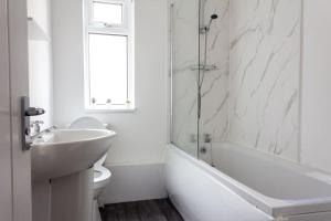 ein weißes Badezimmer mit einem Waschbecken, einer Badewanne und einem WC in der Unterkunft Modern 5 Bed Near LFC Stadium in Liverpool