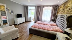 a bedroom with a bed and a chair and a mirror at Penzion Valkoun-Lilienfeld in Karlovy Vary