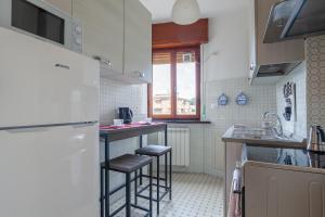 a kitchen with a white refrigerator and stools in it at Tirrenia Cozy Apartment near the Beach in Tirrenia