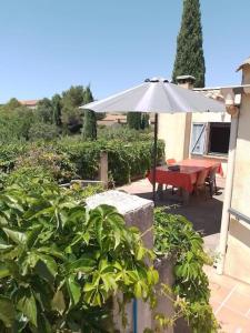 a patio with a table and an umbrella at Maison de charme avec vue sur la vallee de la Ceze in Saint-Gervais