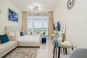 a living room with a white couch and a glass table at Tanin - Studios at Damac Hills Carson Tower C in Dubai