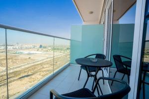 a balcony with a table and chairs and a view at Tanin - Studios at Damac Hills Carson Tower C in Dubai