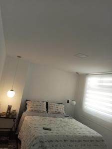 a white bedroom with a bed and a window at nuevo amanecer in Bello