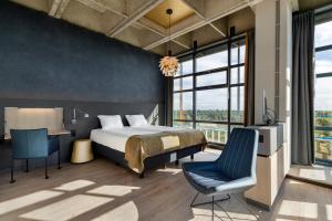 a bedroom with a bed and a desk and a chair at U Parkhotel in Enschede