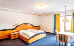 ein Hotelzimmer mit einem Bett und einem Tisch in der Unterkunft Hotel Reipertingerhof in Bruneck